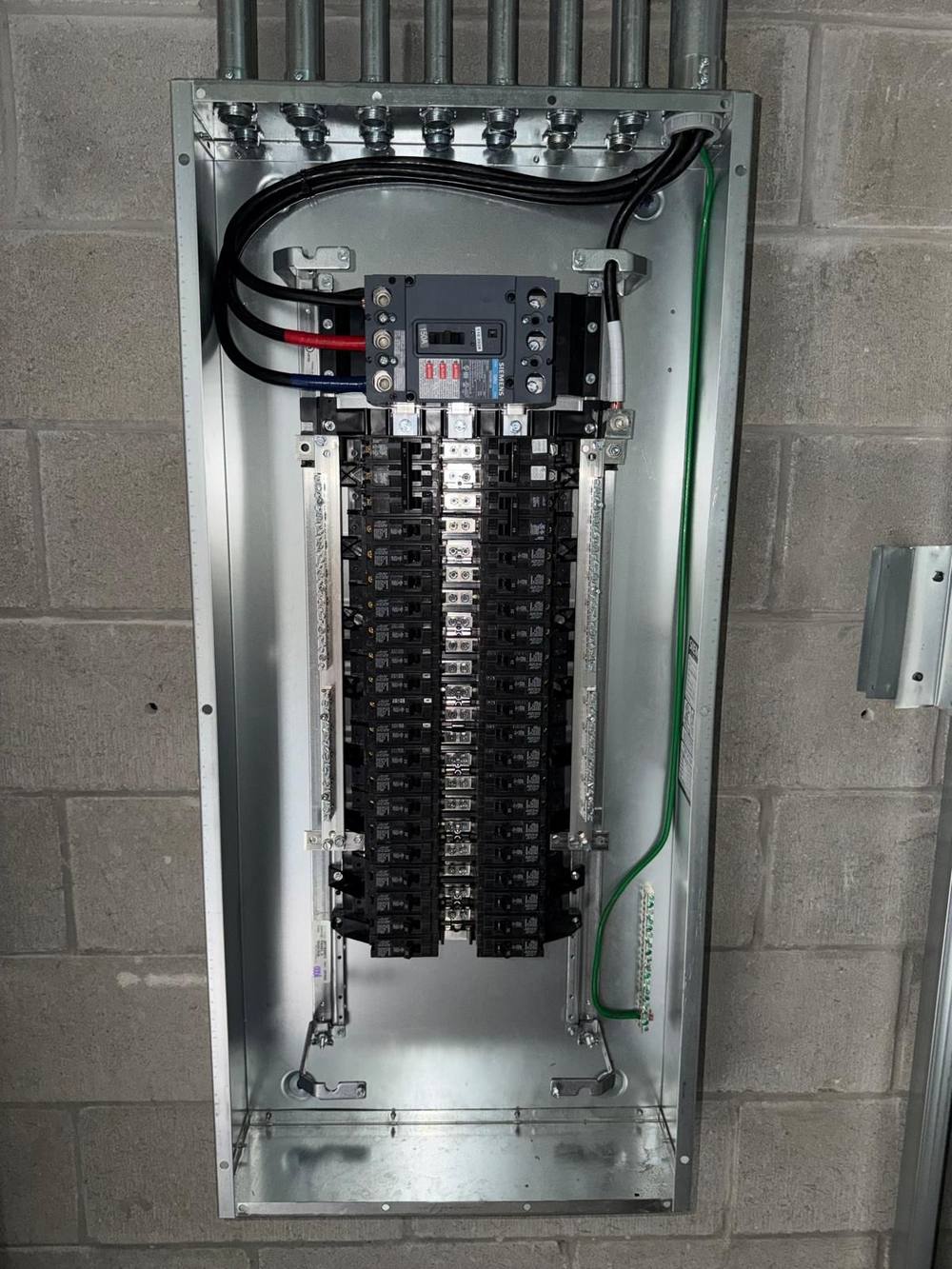 Twin panelboards mounted with main breaker and rigid conduit feeds