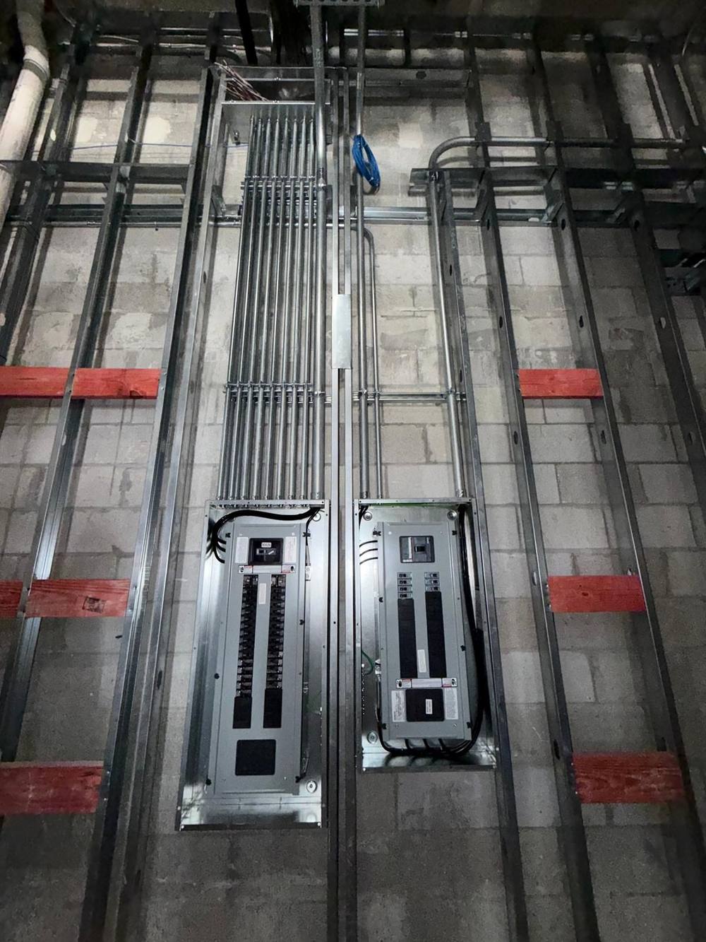 Twin panelboards with rigid conduit stub-ups overhead